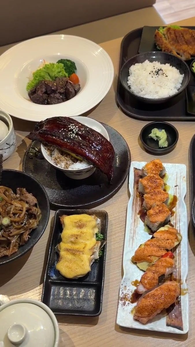 Table seen from above: beef salad, eel don, onion beef don, baked scallops, seared mentai sushi and a pork cutlet set